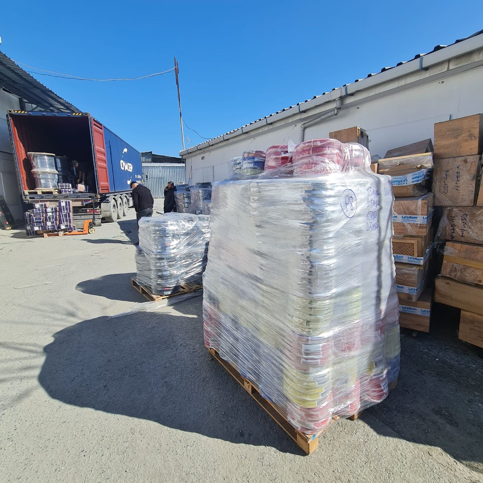 Palettes filmées de tourets de câbles à côté d'un conteneur ouvert au dépôt TED